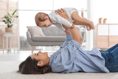Happy young mother playing with baby on floor at home