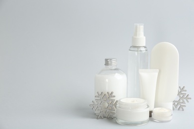 Beautiful composition with cosmetic products on light grey background, space for text. Winter care