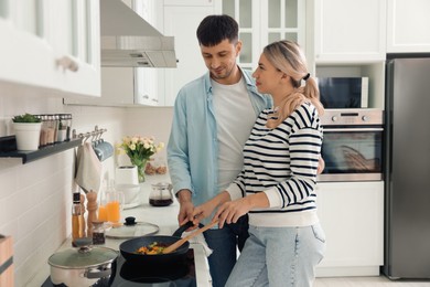 Photo of Happy couple cooking breakfast together in kitchen