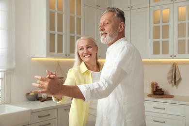 Happy senior couple dancing together in kitchen