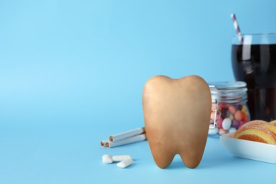 Tooth model with cute face, gums and harmful products on light blue background. Space for text