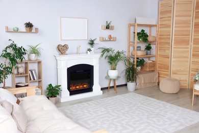 Photo of Stylish living room interior with fireplace, houseplants and carpet