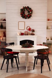Cozy dining room interior with beautiful Christmas wreath and fireplace