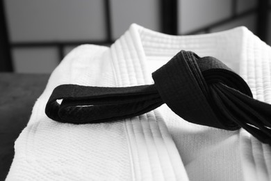 Martial arts uniform with black belt on table indoors, closeup