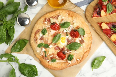 Photo of Delicious homemade pita pizza and basil on white marble table, flat lay