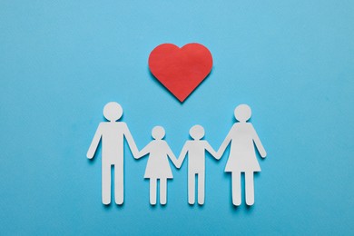 Paper family figures and red heart on light blue background, flat lay. Insurance concept