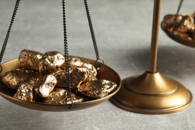 Vintage scales with gold nuggets on light grey table, closeup