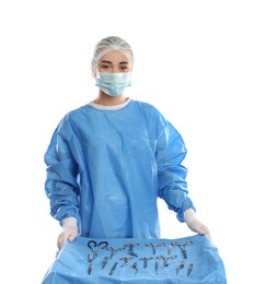 Doctor near table with surgical instruments on light background