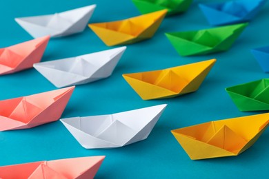 Photo of Many colorful handmade paper boats on light blue background. Origami art