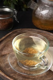 Buckwheat tea in glass cup on wooden tray, closeup