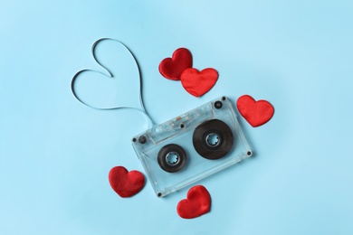 Music cassette and red hearts on light blue background, flat lay. Listening love song