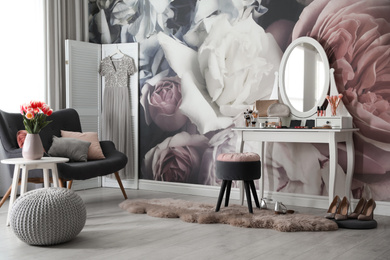 Stylish room interior with elegant dressing table, sofa and floral wallpaper