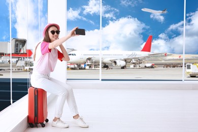 Happy young woman taking selfie in airport