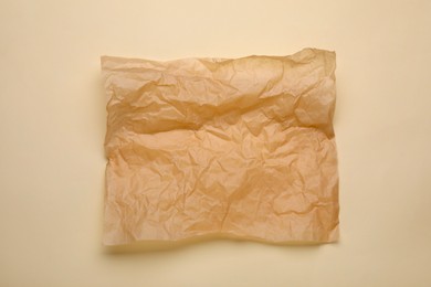 Sheet of crumpled baking paper on beige background, top view