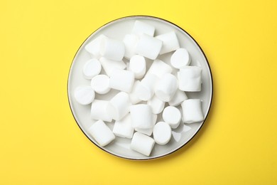 Delicious puffy marshmallows on yellow background, top view
