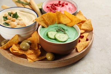 Different kinds of tasty hummus served with snacks on light table