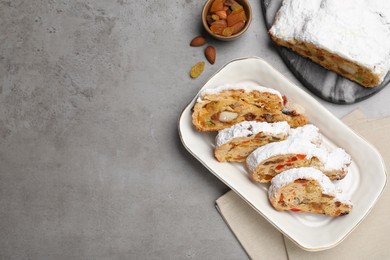 Traditional Christmas Stollen with icing sugar on grey table, flat lay. Space for text
