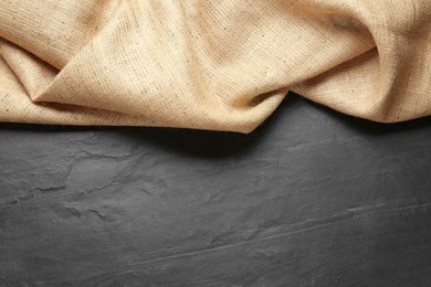 Natural burlap fabric on black table, top view. Space for text