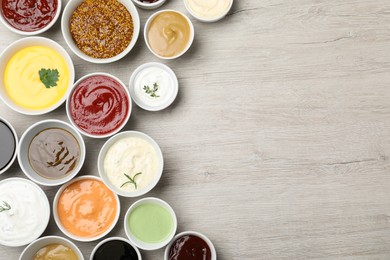 Many different sauces on white wooden table, flat lay. Space for text