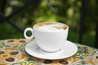 Cup of aromatic coffee on beautiful table in cafe outdoors