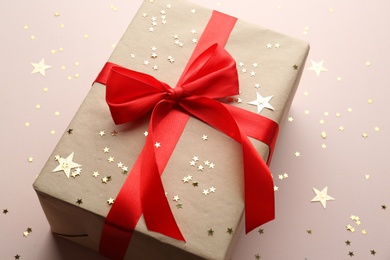 Gift box and confetti stars on light background, closeup. Christmas celebration