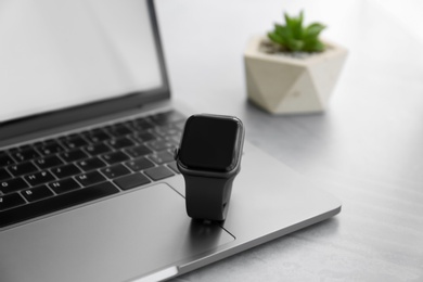 Stylish smart watch and laptop on grey table, closeup