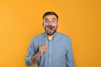 Photo of Emotional man with fake mustache on yellow background