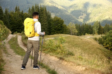 Photo of Man with backpack and trekking poles on trail, space for text. Tourism equipment