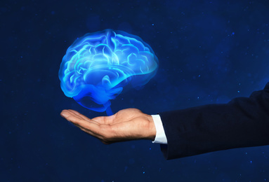 Image of Young man holding digital image of brain on blue background, closeup