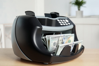Modern electronic bill counter with money on table indoors