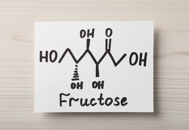 Photo of Paper with word Fructose and drawn scheme on white wooden table, top view