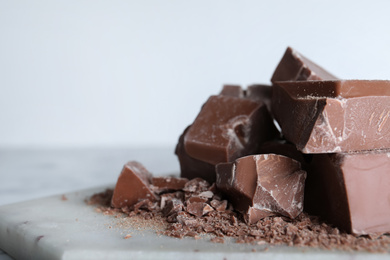 Photo of Pieces of tasty milk chocolate on board, closeup