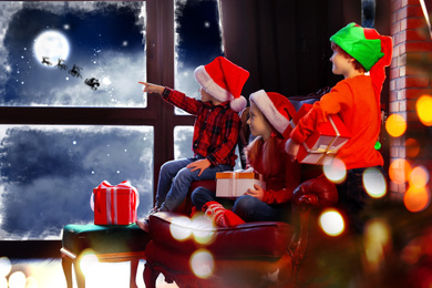 Image of Cute little children waiting for Santa Claus near window at home. Christmas holiday