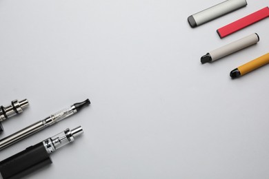Many electronic smoking devices on white background, flat lay. Space for text