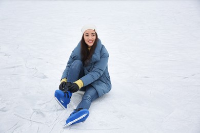 Woman adjusting figure skate while sitting on ice rink. Space for text