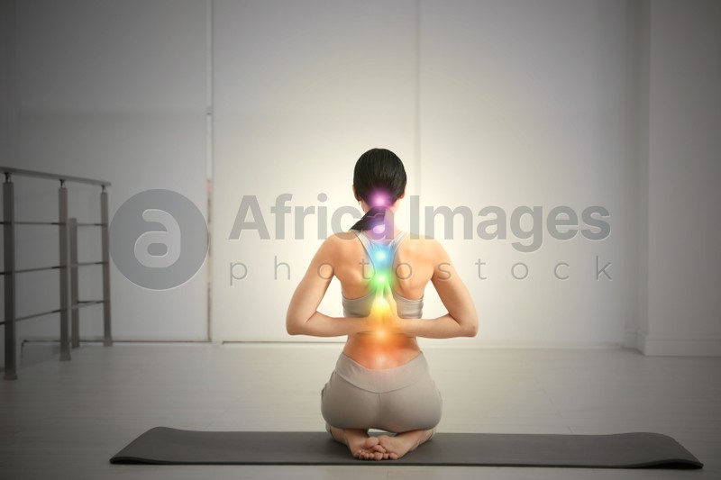 Image of Young woman with chakra points practicing yoga in studio, back view. Healing energy 