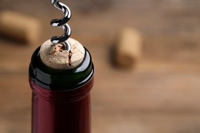 Opening wine bottle with corkscrew on table, closeup. Space for text