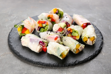 Delicious rolls wrapped in rice paper on grey table