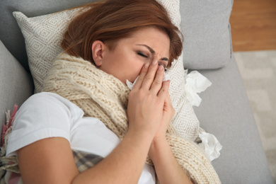 Sick woman lying on sofa at home. Influenza virus