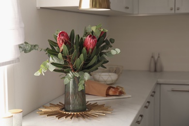 Photo of Bouquet with beautiful protea flowers on countertop in kitchen, space for text. Interior design