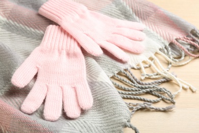 Stylish gloves and scarf on white wooden background, closeup