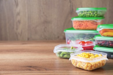 Set of plastic containers with fresh food on wooden  table, space for text