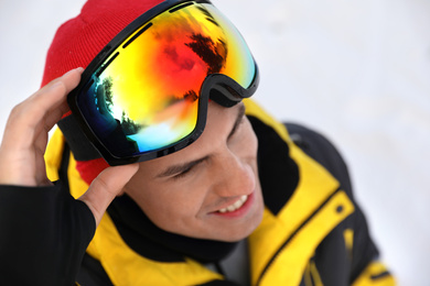 Handsome man at ski resort, focus on goggles. Winter sports equipment