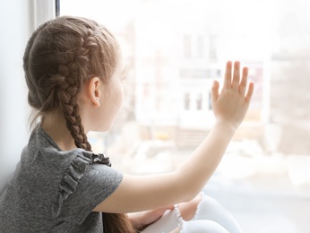Lonely little girl near window indoors. Child autism