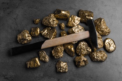 Gold nuggets and hammer on grey table, flat lay