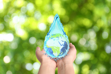 Woman holding icon of Earth in water drop on blurred green background, closeup. Ecology concept