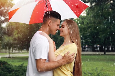 Lovely couple with umbrella walking under rain in park