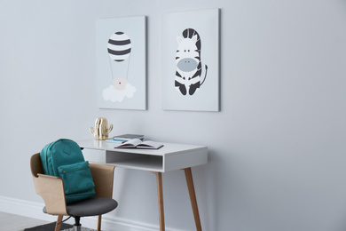 Photo of Child's room interior with desk and cute posters on light wall. Space for text