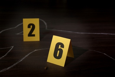 Crime scene with chalk outline of human body, bullet shell and evidence markers on wooden floor. Detective investigation