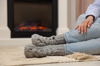 Woman resting near fireplace at home, closeup